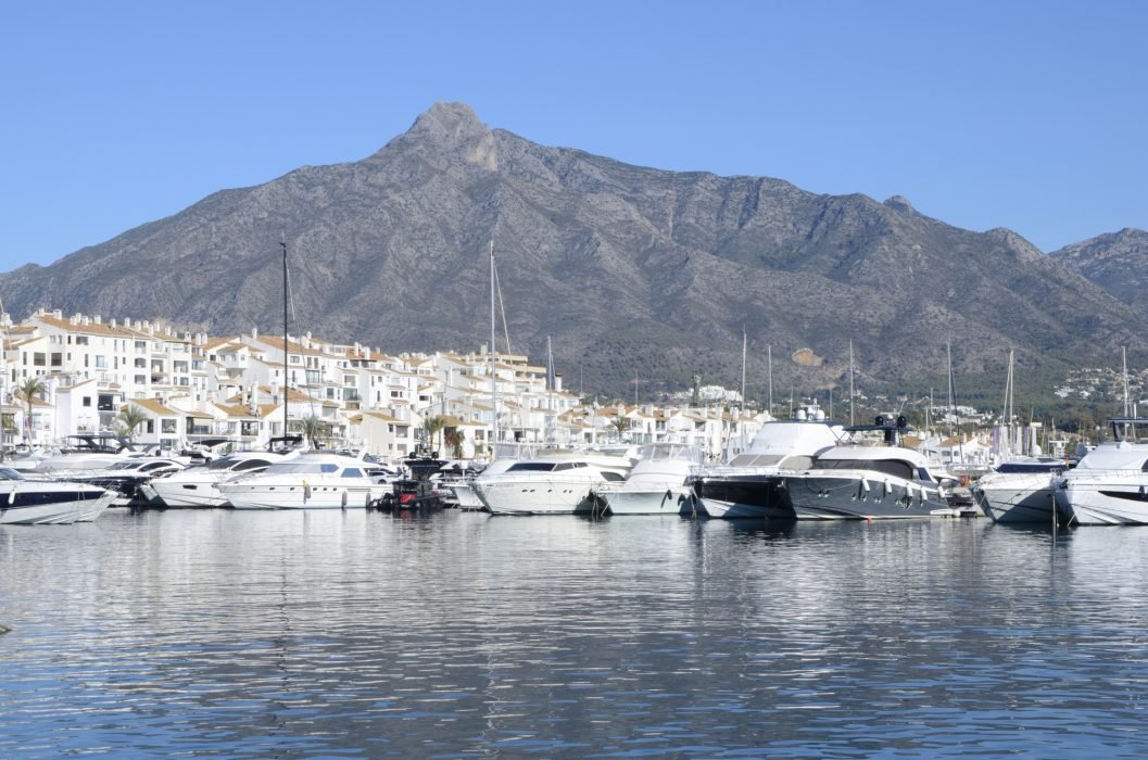 Marbella, Spain - December 10, 2023: White boats and houses in Port Banus at the foot of the mountain in Marbella, Andalusia, Spain.